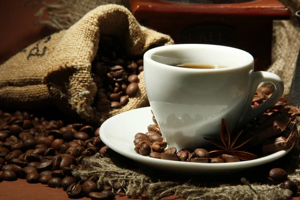 Kopp kaffe, kvarn, turk och kaffebönor på brun bakgrund — Stockfoto