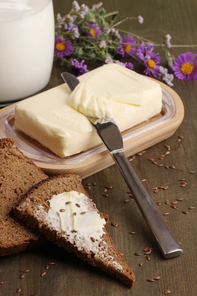 Masło na drewnianym uchwytem otoczony chleb i mleko na drewniany stół szczegół — Zdjęcie stockowe