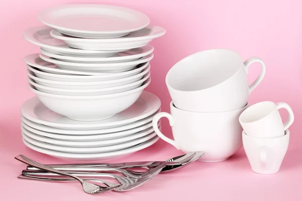 Чистые белые блюда на розовом фоне — стоковое фото