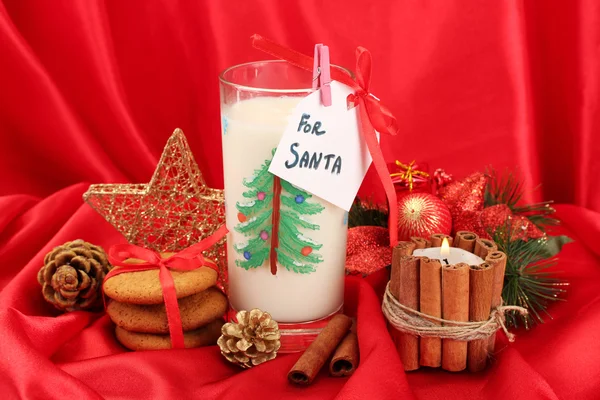 Galletas para Santa: Imagen conceptual de galletas de jengibre, leche y decoración navideña sobre fondo rojo —  Fotos de Stock