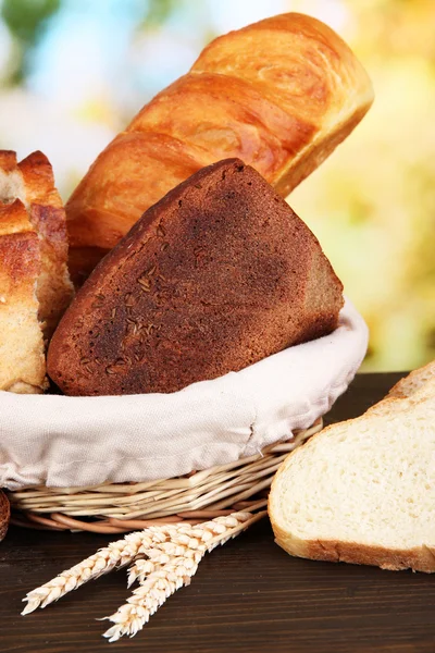 Fresh bread in basket on wooden table on natural background close-up — Stock Photo, Image