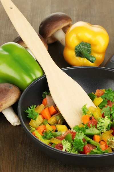Skivade färska grönsaker i stekpanna med kryddor och ingredienser på träbord — Stockfoto