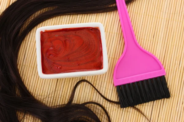 Hair dye in bowl and brush for hair coloring on beige bamboo mat, close-up Royalty Free Stock Photos