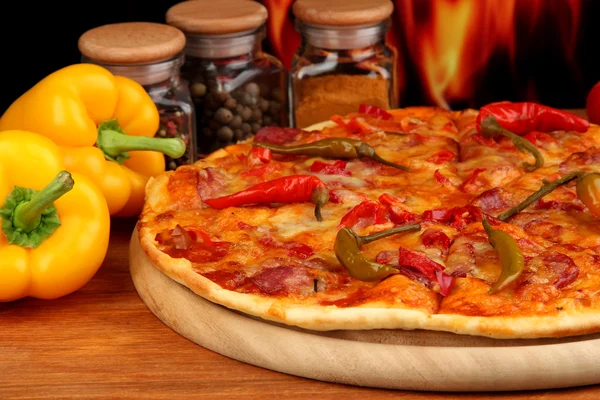 与火焰背景上的木制板上蔬菜美味意大利辣香肠比萨饼 — 图库照片