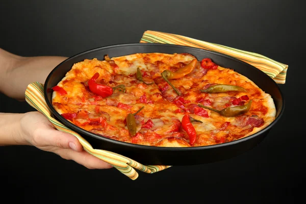 Hands holding pepperoni pizza in pan on grey background — Stock Photo, Image