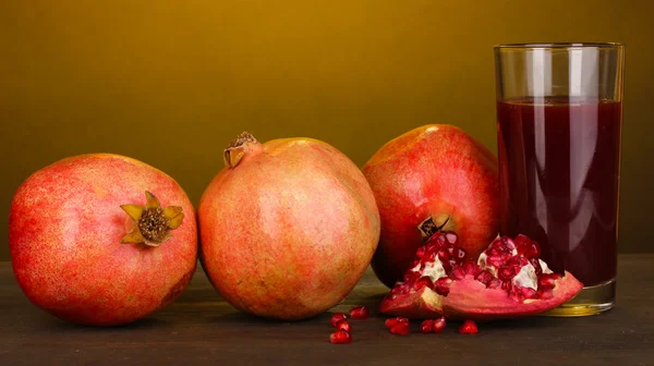 Granadas maduras con vaso de jugo de granada sobre fondo amarillo — Foto de Stock