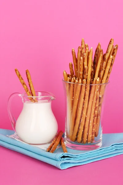 Leckere knusprige Sticks im Glasbecher auf rosa Hintergrund — Stockfoto