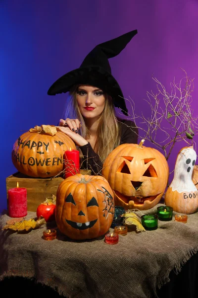 Хэллоуинская ведьма с тыквами на цветном фоне — стоковое фото