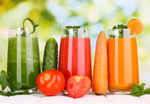 Jugos de verduras frescas sobre mesa de madera, sobre fondo verde — Foto de Stock