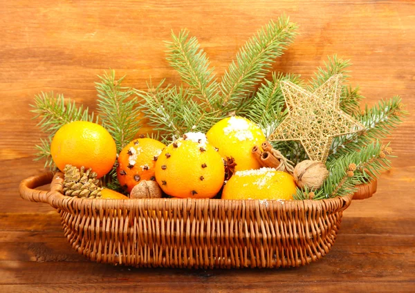 Рождественская композиция в корзине с апельсинами и елкой, на деревянном фоне — стоковое фото