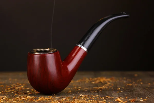 Smoking pipe and tobacco on wooden table on black background — Stock Photo, Image