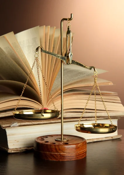 Balance d'or de la justice et livres sur fond marron — Photo