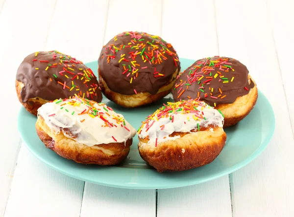 Donuts savoureux sur plaque de couleur sur fond bois clair — Photo