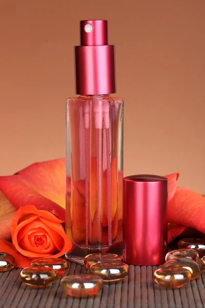 Женские духи в красивой бутылке с розой на коричневом фоне — стоковое фото