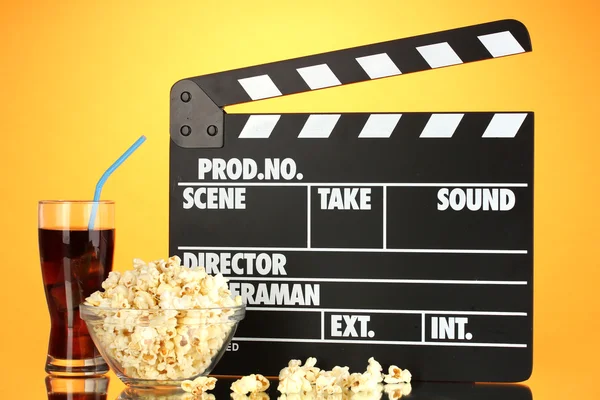 Película clapperboard, cola y palomitas de maíz sobre fondo naranja — Foto de Stock