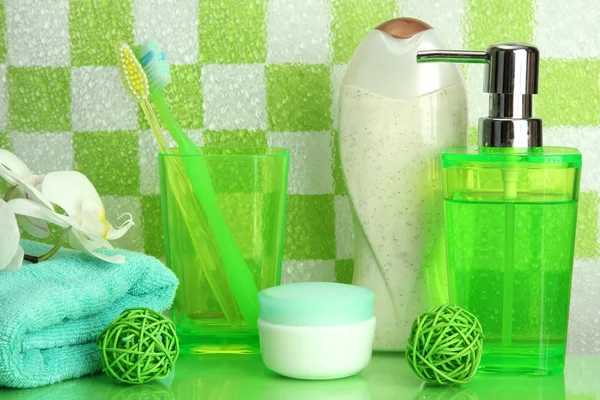 Аксессуары для ванны на полке в ванной комнате на фоне зеленой плитки — стоковое фото