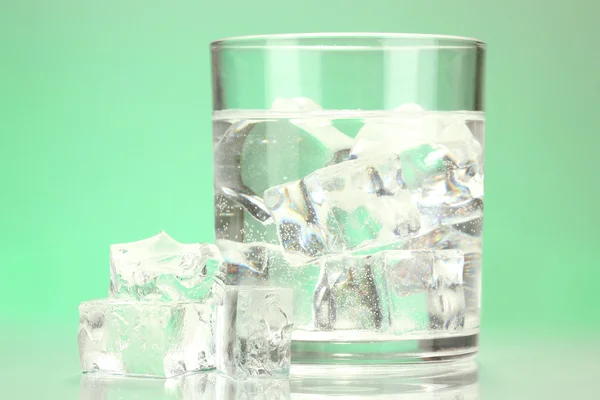 Ice cubes in glass on light green background — Stock Photo, Image