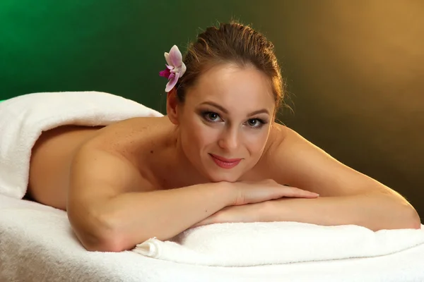 Piękna młoda kobieta w salonie spa, na zielonym tle — Zdjęcie stockowe