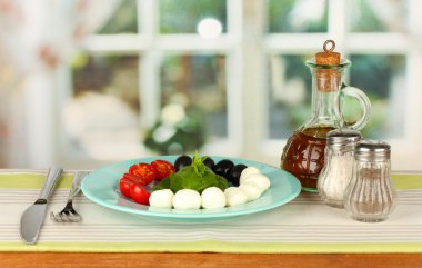 peynir Mozzarella peyniri çatal ve bıçak ahşap masa üzerinde plaka sebze ile