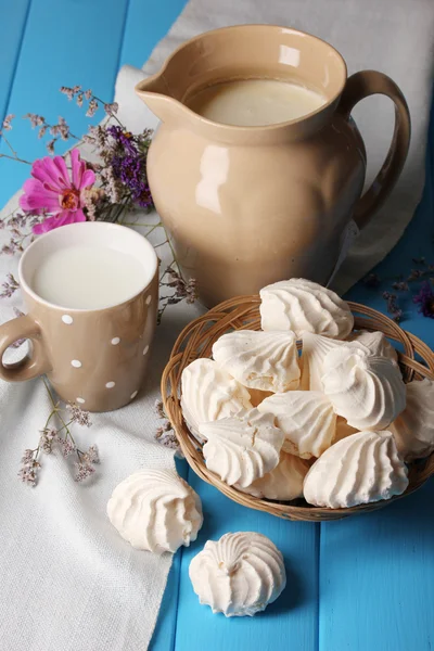 Werper en kopje melk met schuimgebakjes op houten tafel close-up — Stockfoto