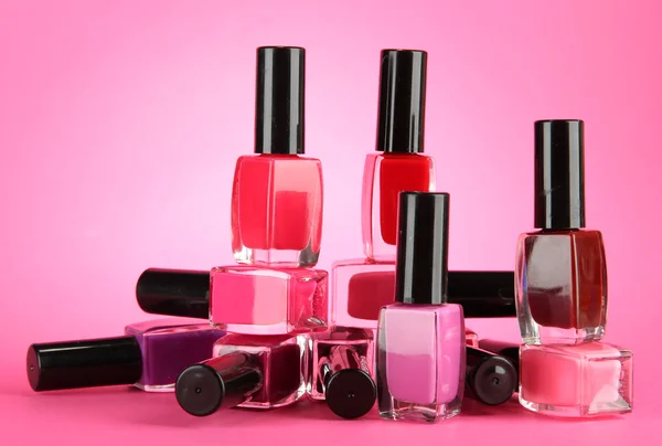 Group of bright nail polishes, on pink background — Stock Photo, Image