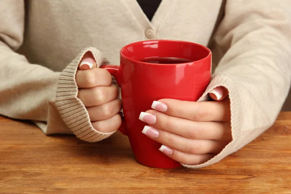 Le mani che tengono la tazza di bevanda calda, primo piano — Foto Stock