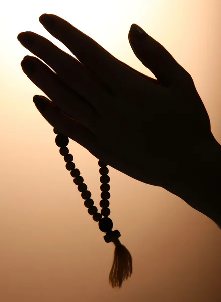 茶色の背景に数珠を持つ女性の手 — ストック写真