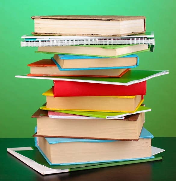 Stack of interesting books and magazines on wooden table on green background — Stock Photo, Image