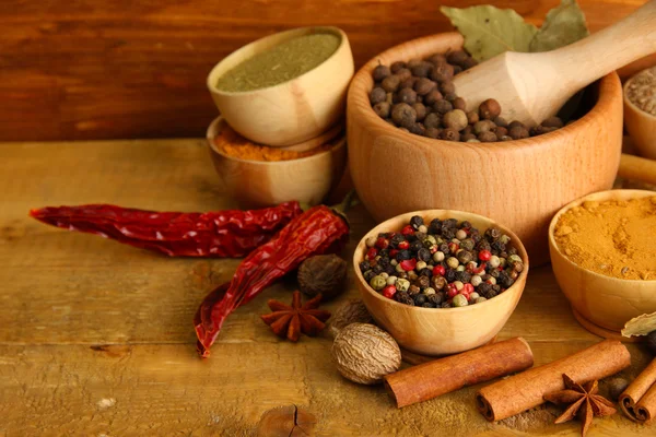 Murbruk, skålar och skedar med kryddor, på trä bakgrund — Stockfoto