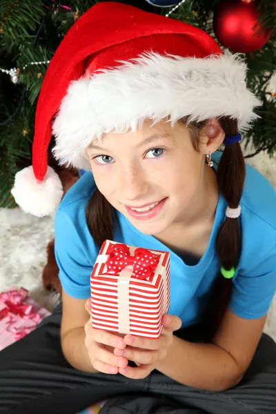 Kleines Mädchen hält Geschenkbox in der Nähe des Weihnachtsbaums — Stockfoto