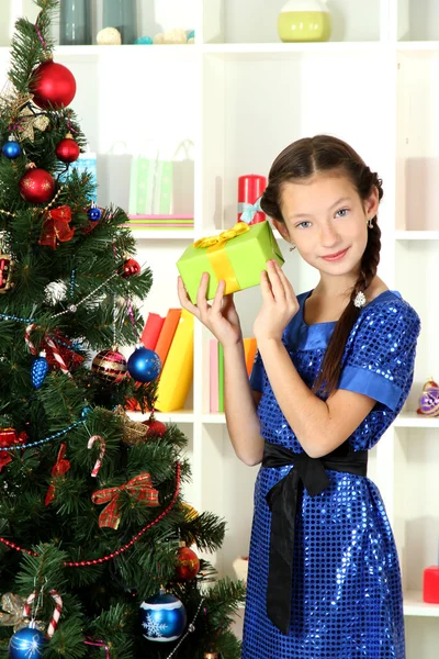 Kleines Mädchen hält Geschenkbox in der Nähe des Weihnachtsbaums — Stockfoto