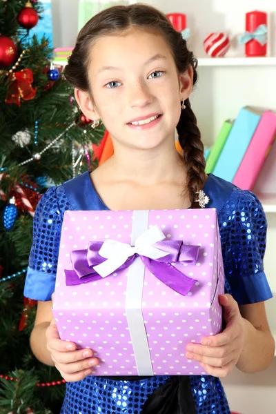 Little girl holding gift box near christmas tree — Stock Photo, Image