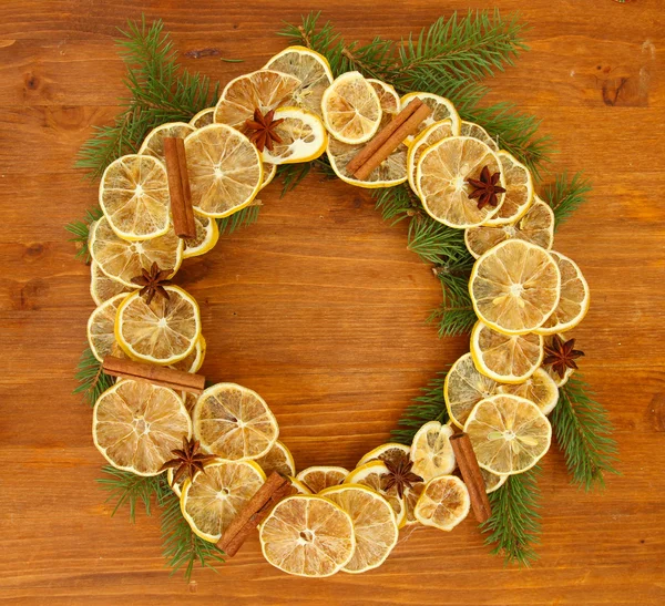 Weihnachtskranz aus getrockneten Zitronen mit Tanne auf Holzgrund — Stockfoto