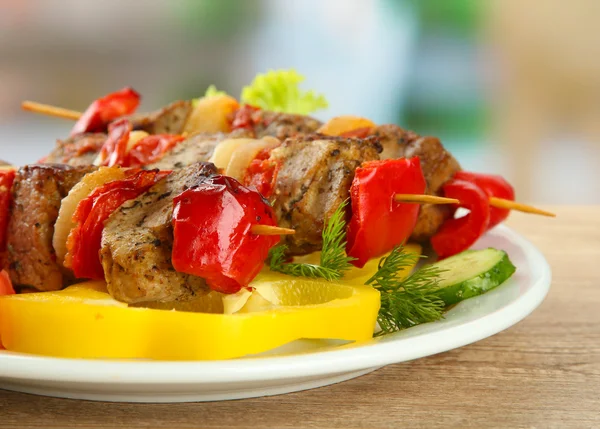 Tasty grilled meat and vegetables on skewer on plate, on wooden table — Stock Photo, Image