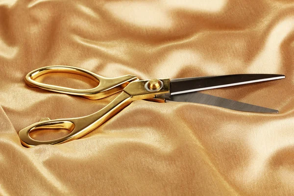 Metal scissors on gold fabric — Stock Photo, Image