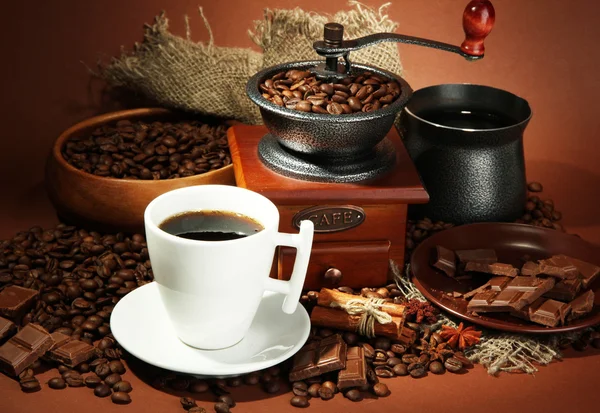 Cup of coffee, grinder, turk and coffee beans on brown background — Stock Photo, Image