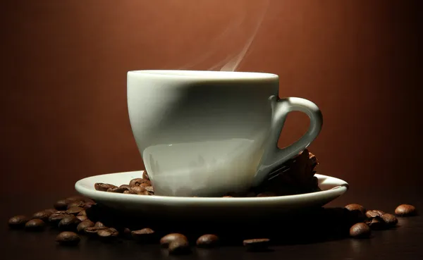 Cup of coffee with beans on table, on brown background — Stock Photo, Image