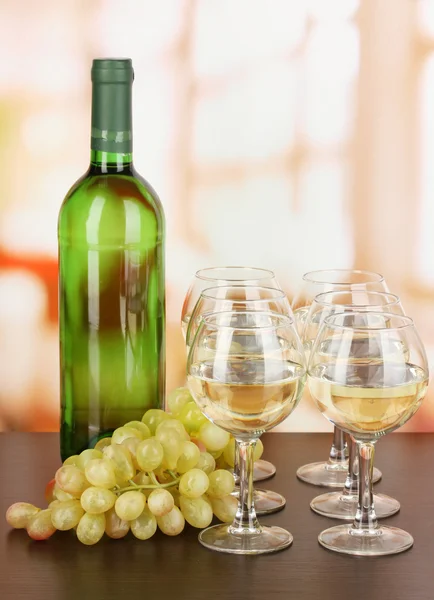 Vin blanc en verre et bouteille sur fond de pièce — Photo