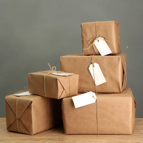 Cajas de paquetes con papel kraft, sobre mesa de madera sobre fondo gris —  Fotos de Stock