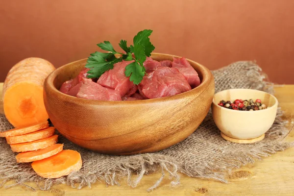 Carne di manzo cruda marinata con erbe e spezie su tavolo di legno su sfondo marrone — Foto Stock