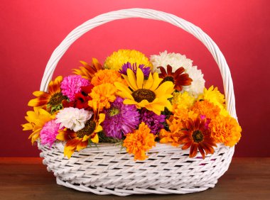 güzel ahşap masa üzerinde pembe bir arka plan üzerinde beyaz sepet içinde parlak çiçek buketi