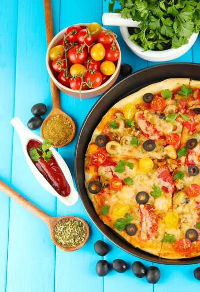 Composición colorida de deliciosa pizza, verduras y especias sobre fondo de madera azul de cerca —  Fotos de Stock