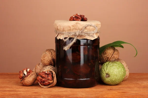 Jam-jar of walnuts on wooden table on brown background — Stock Photo, Image