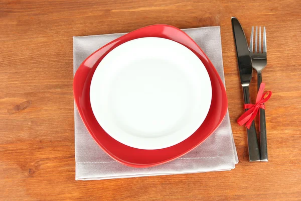 Placas vermelhas e brancas vazias com garfo e faca na mesa de madeira, close-up — Fotografia de Stock