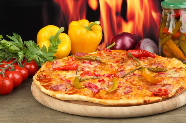 Välsmakande pepperoni pizza med grönsaker på träplatta på lågan bakgrund — Stockfoto