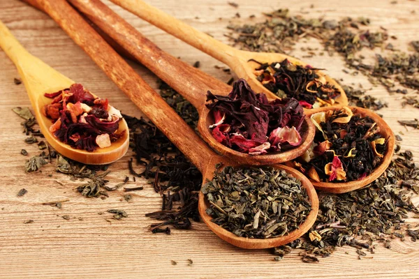 Assortment of dry tea in spoons, on wooden background — Stock Photo, Image