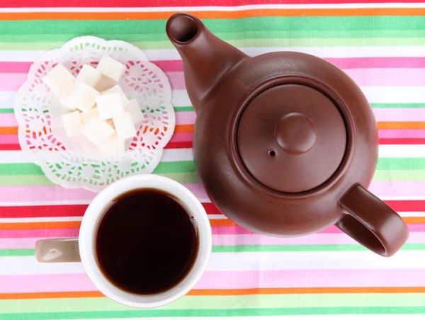 Bovenaanzicht van een kop van thee en theepot op kleurrijke tafelkleden — Stockfoto