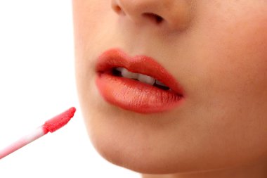 beautiful young woman applying lip gloss, isolated on white