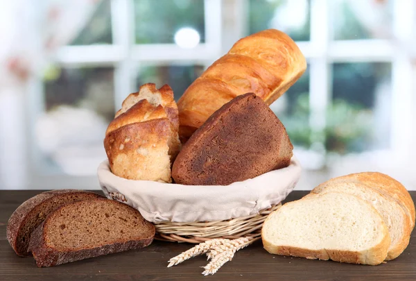 Pane fresco in cesto su tavolo di legno su sfondo finestra — Foto Stock