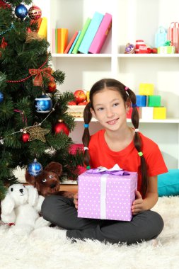hediye kutusu Noel ağacının yakınında tutan küçük bir kız